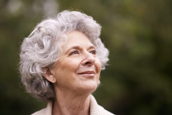 Woman with grey hair smiling confidently.