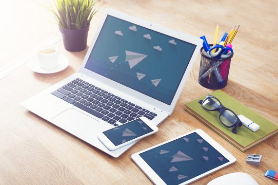 Table with computer, tablet, phone, and office supplies.