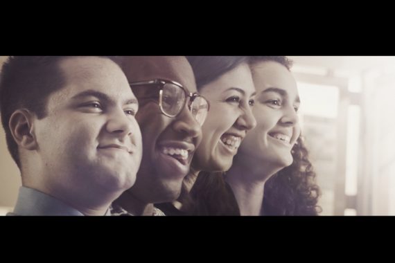 Four people smiling and laughing facing the same direction