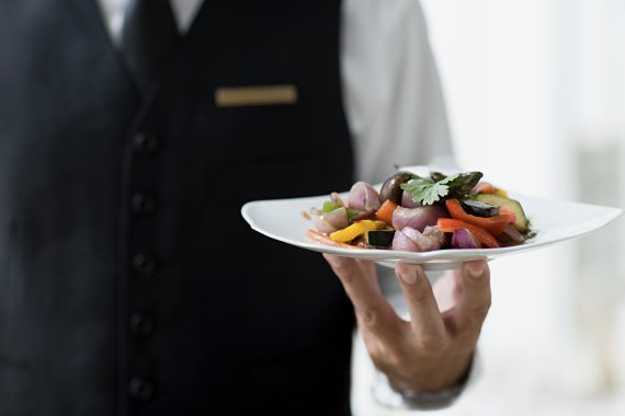 Table waiting staff with a plate of cold salad.