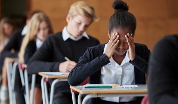 student at desk with head in hands
