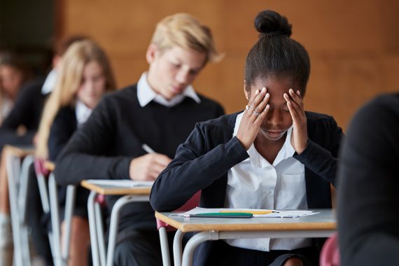 student at desk with head in hands
