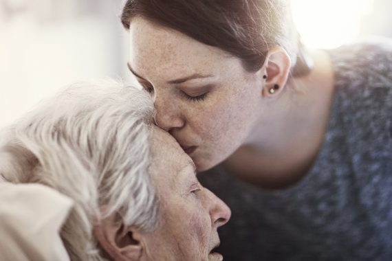 Woman kissing older woman's forehead