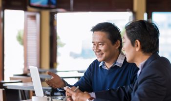 Business meeting with two happy people at a cafe table with computer.